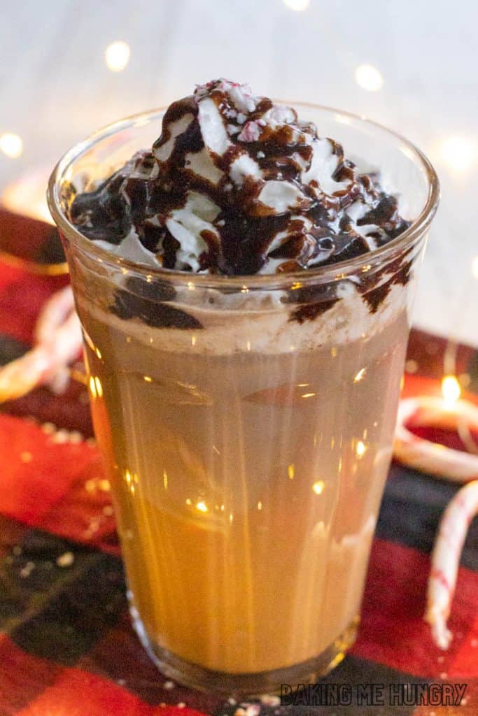 iced peppermint mocha in a glass close up in front of twinkle lights