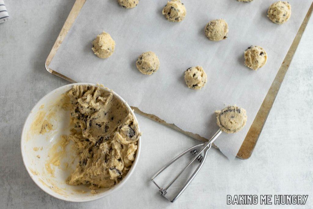scoop next to bowl of dough with dough balls on parchment