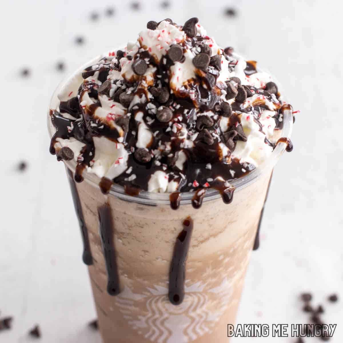 peppermint mocha frappuccino recipe in Starbucks cup topped with whipped cream, crushed candy canes, and mini chocolate chips