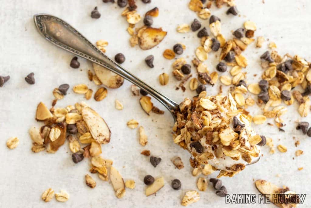 spoon with chocolate granola with more scattered on backdrop
