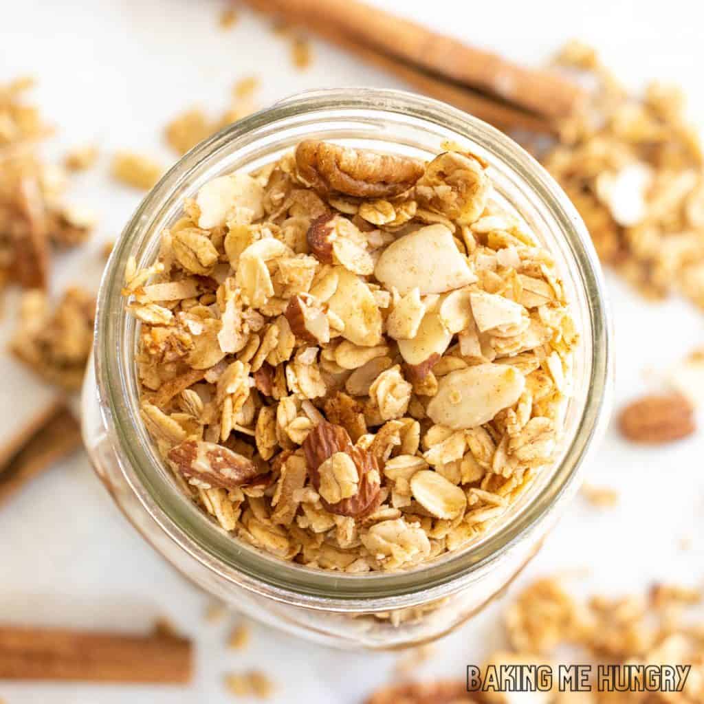 cinnamon granola recipe stored in mason jar with cinnamon sticks around the bottom
