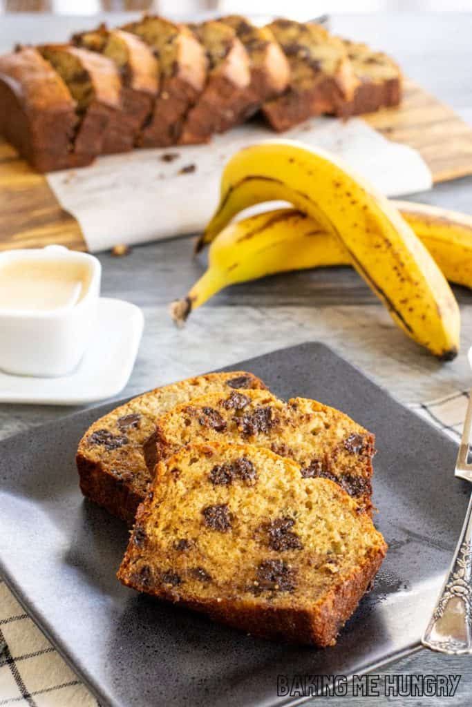slices of brown butter chocolate chip banana bread on plate with remaining bread behind