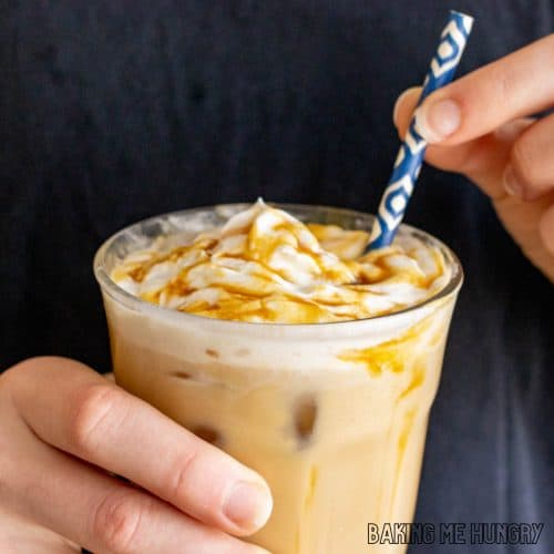 caramel iced coffee recipe in glass being held by two hands