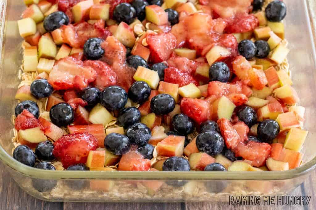 berries and rhubarb on top of oats in baking dish