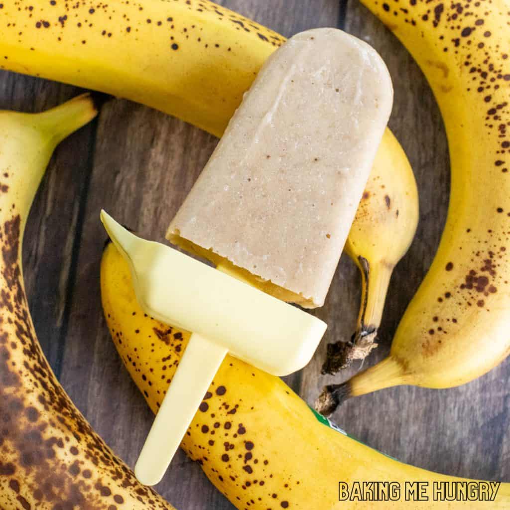 creamy banana popsicles recipe creamy banana popsicle resting on fresh bananas
