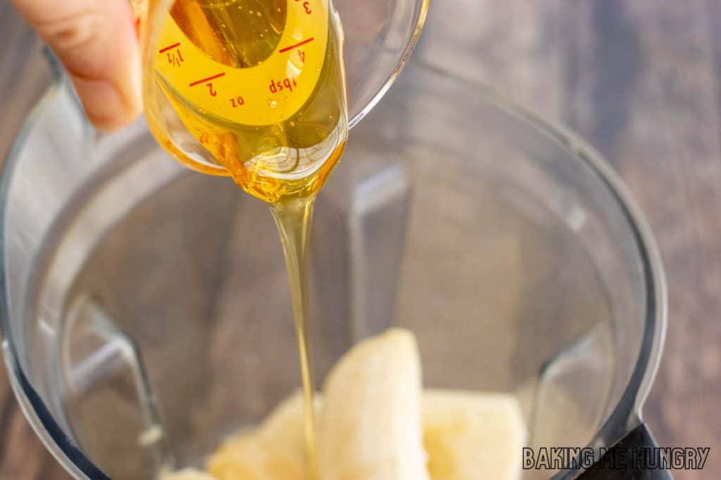 creamy banana popsicles recipe honey being added to blender