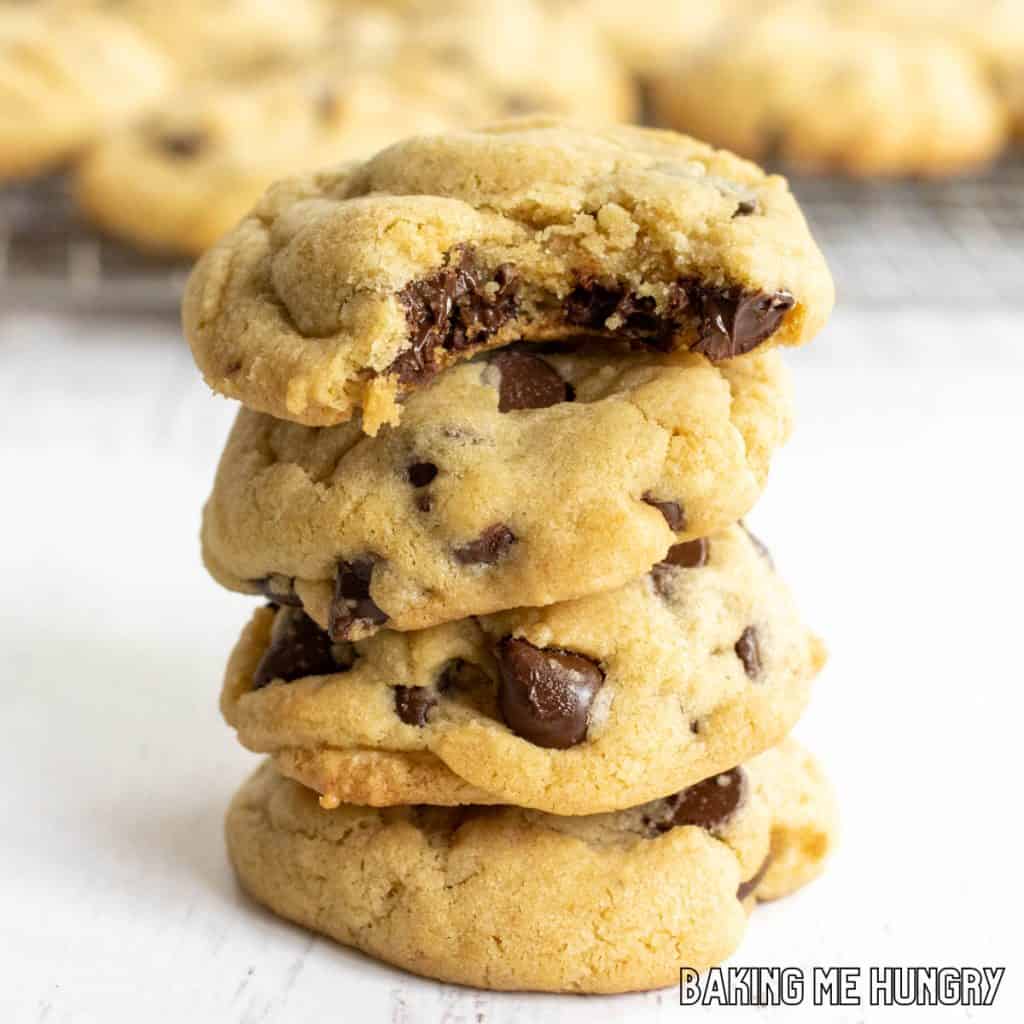 brown sugar chocolate chip cookies in a stack with the top cookie missing a bite and rack of cookies behind