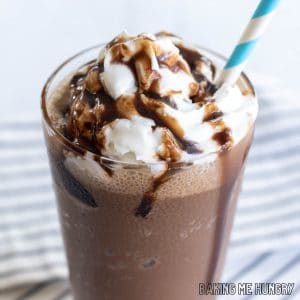 chocolate slushy recipe close up in a glass with whipped cream, chocolate syrup, and a straw from the side