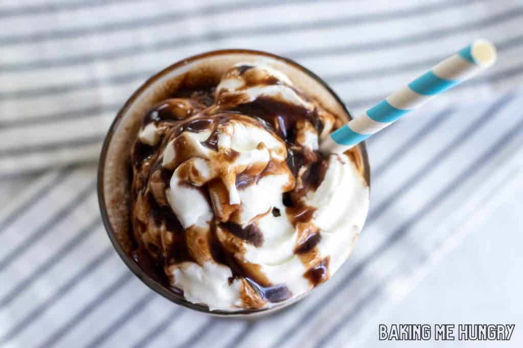 chocolate slushy recipe in a glass with whipped cream, chocolate syrup, and a straw from overhead