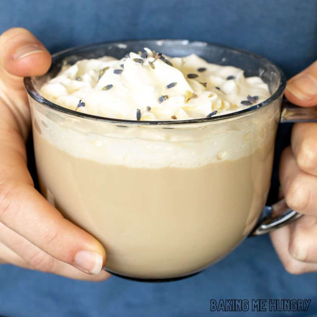 lavender latte recipe in glass mug held by two hands