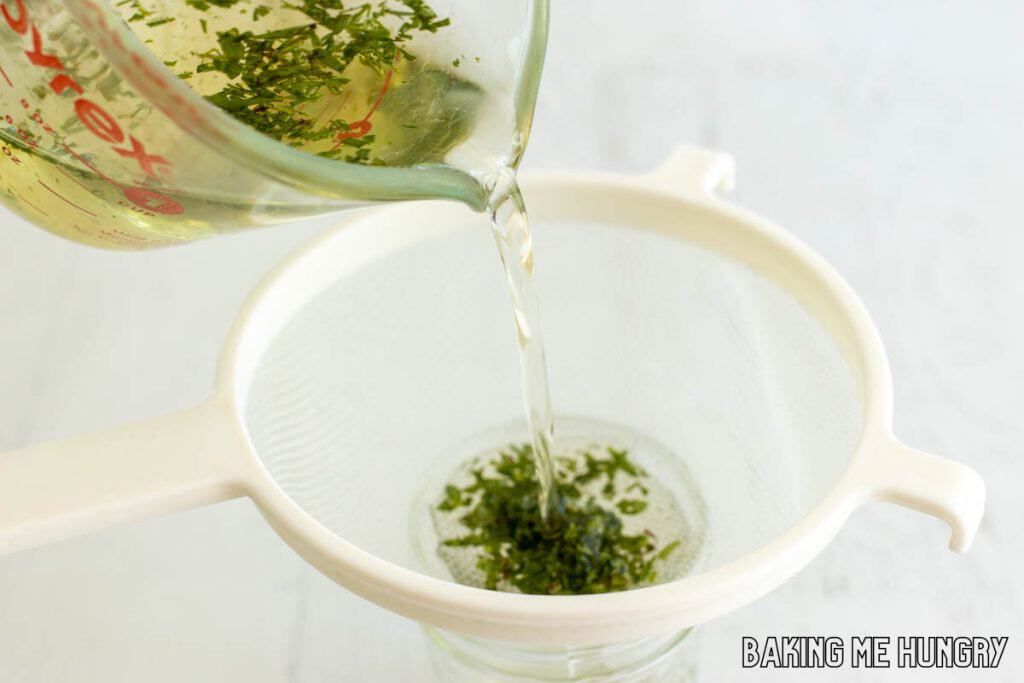 lavender syrup being poured through strainer