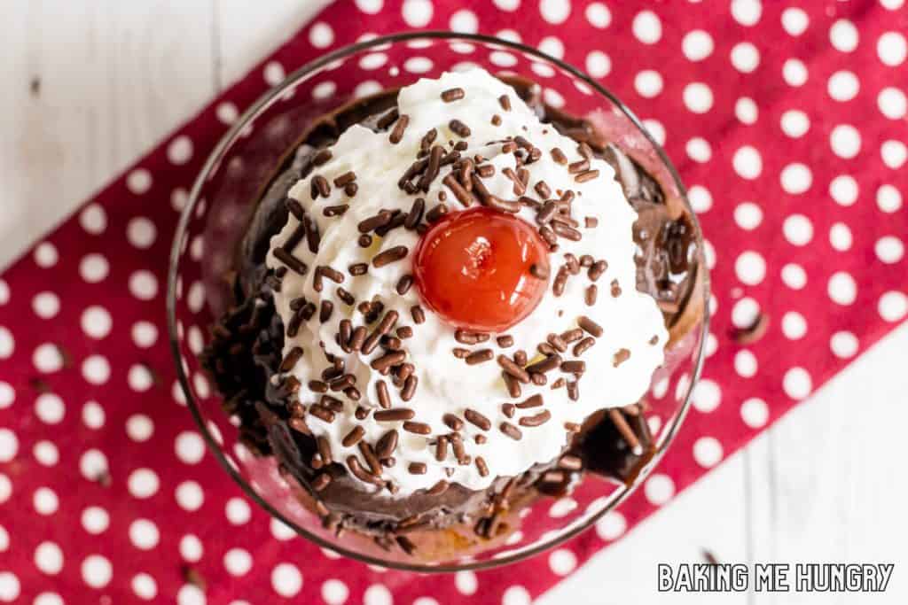 brownie batter ice cream recipe in dish with whipped cream, chocolate sprinkles, and a cherry from overhead