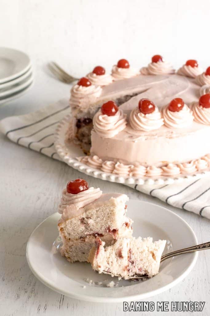 cherry chip cake slice on a plate with bite on a fork and remaining cake behind