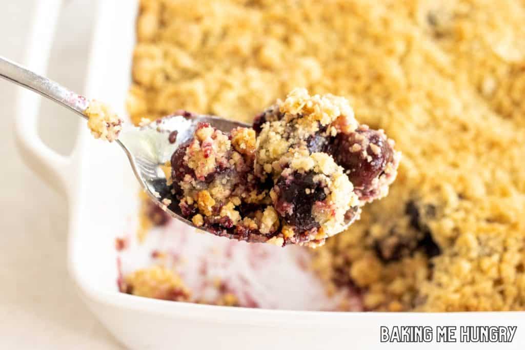 spoon lifting up some of the cherry crumble