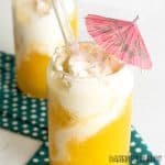 mango slushy recipe close up in two glasses with swirled whipped cream and paper straws