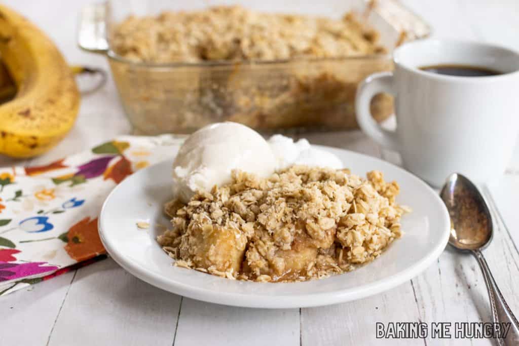 banana crisp served with vanilla ice cream and whipped cream with baking dish behind