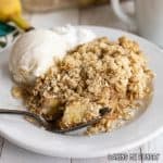 bite of banana crisp on a spoon resting on plate