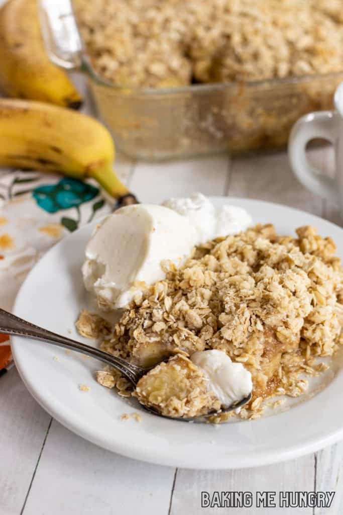 bite of banana crisp with vanilla ice cream on a spoon resting on plate