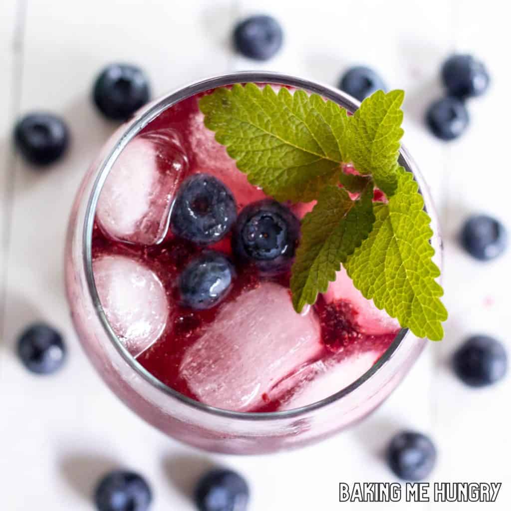 blueberry mocktail recipe from overhead in stemless wine glass with mint and blueberries as garnish