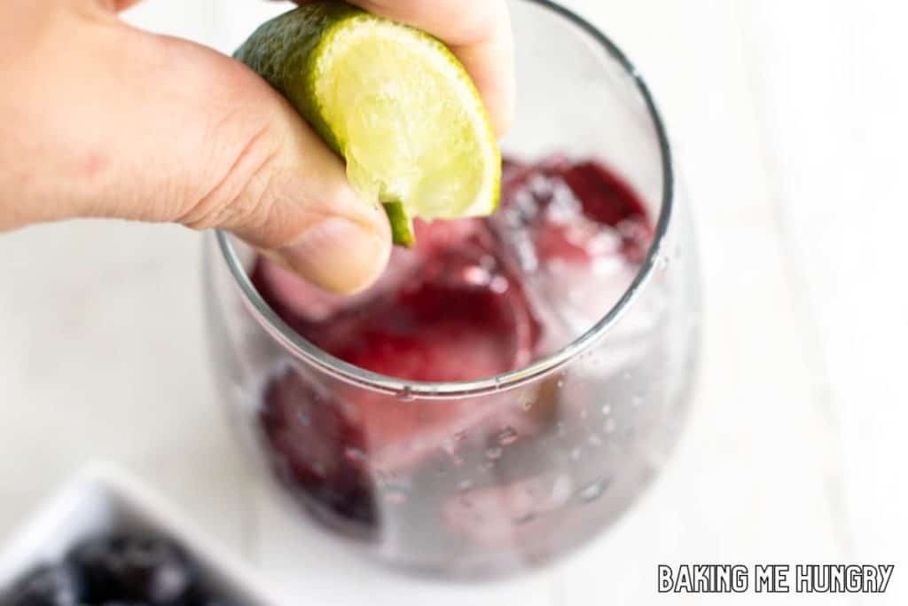 hand squeezing lime into glass