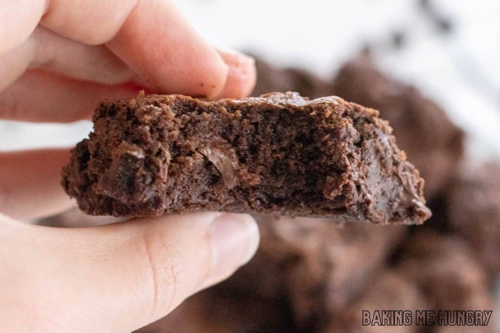 hand holding up one of the double chocolate brownie with a bite missing