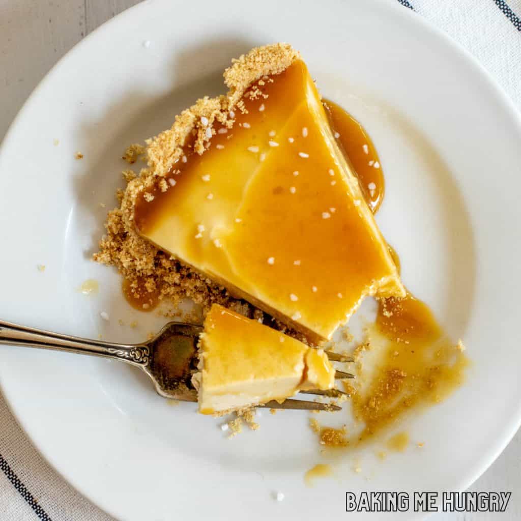 no bake caramel cheesecake slice on plate with coarse salt sprinkled on top and a bite on a fork