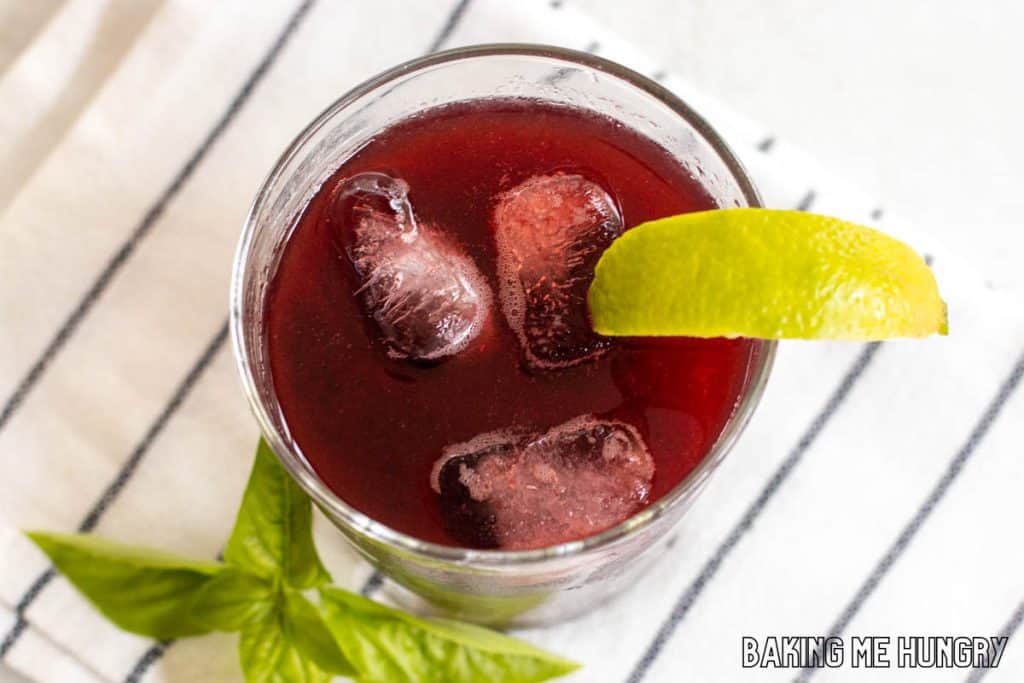 blackberry mocktail in glass from overhead with lime wedge and basil garnish on striped napkin