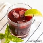 blackberry mocktail close up in glass with lime wedge and basil garnish