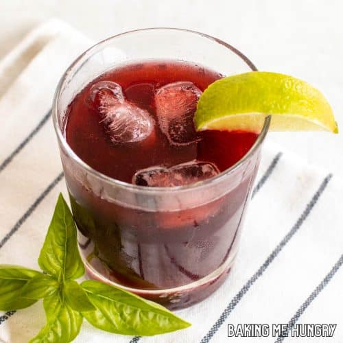 blackberry mocktail close up in glass with lime wedge and basil garnish