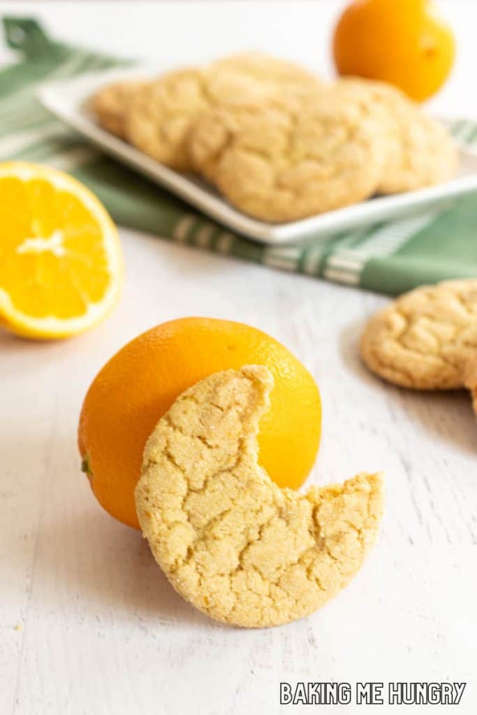 orange sugar cookie with bite missing leaning on an orange