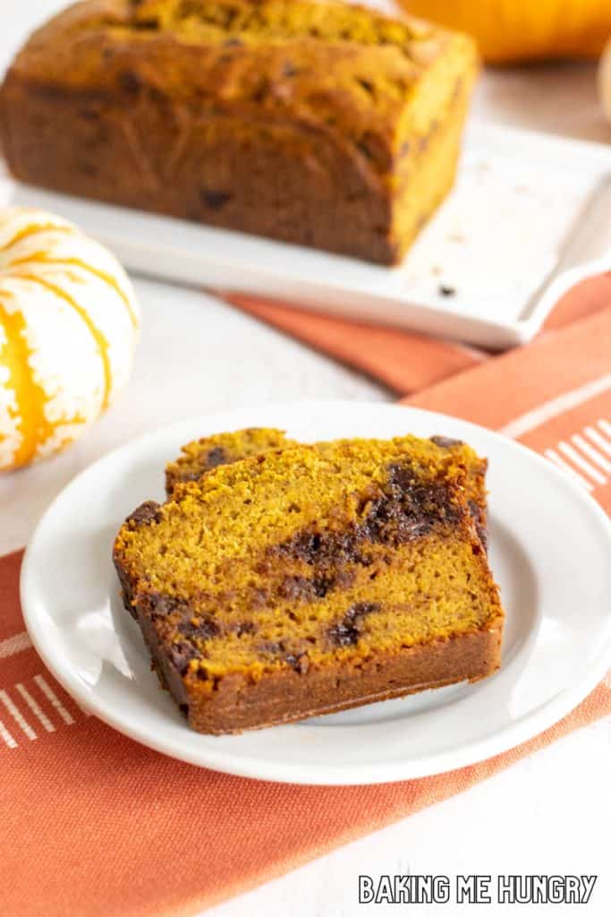 slices of chocolate chip pumpkin banana bread on a plate with loaf behind