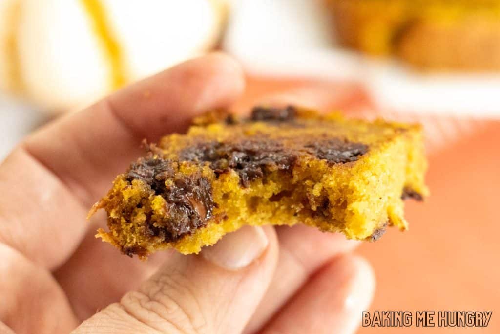 hand holding up a piece of the chocolate chip pumpkin banana bread with a bite missing