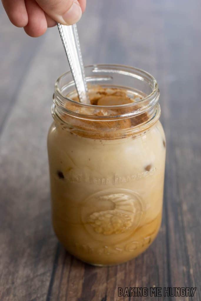 hand holding a spoon stirring drink in mason jar