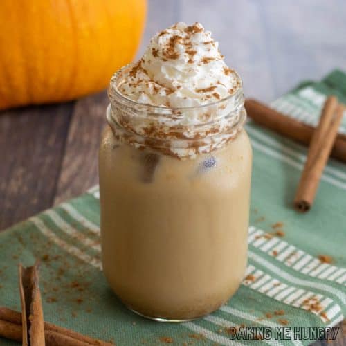iced pumpkin spice latte in a mason jar with whipped cream and cinnamon