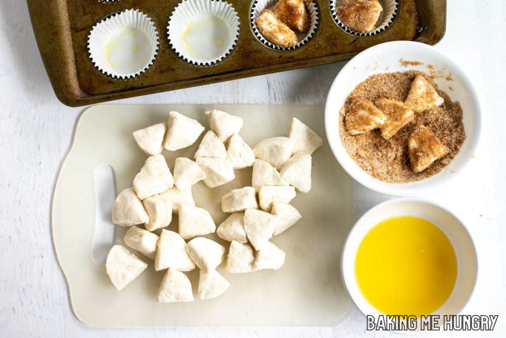 pieces of dough on cutting board next to melted butter in bowl and cinnamon sugar mixture in second bowl