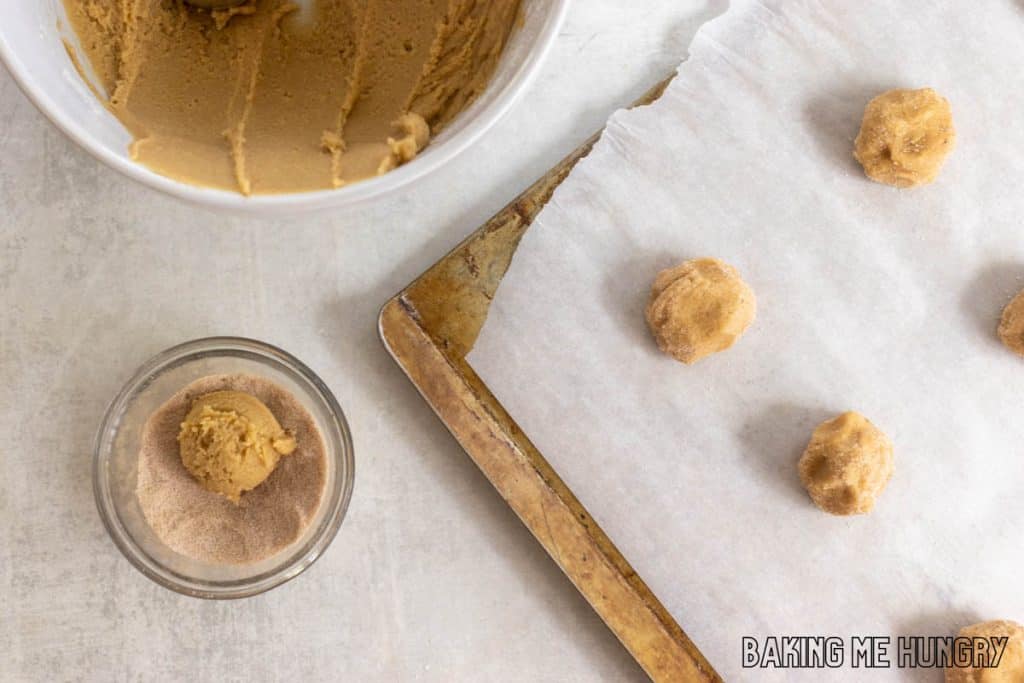balls of dough in sugar mixture and on baking sheet
