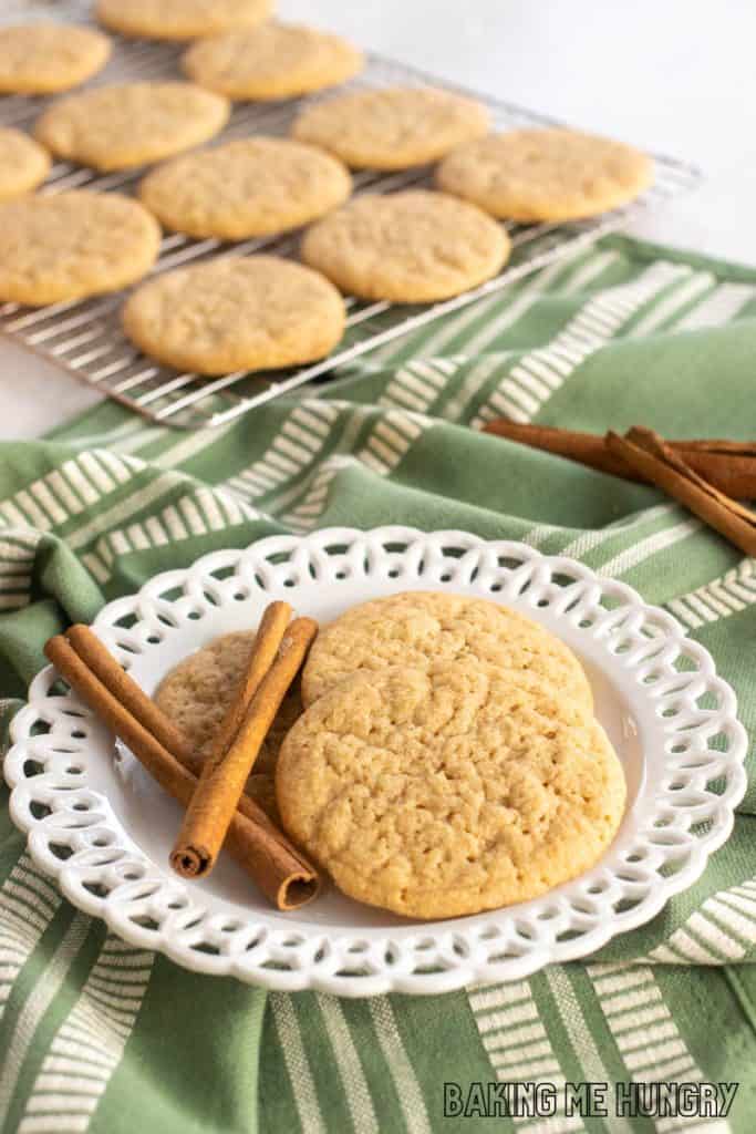 pumpkin spice sugar cookies on a decorative white plate with cooling rack of cookies behind