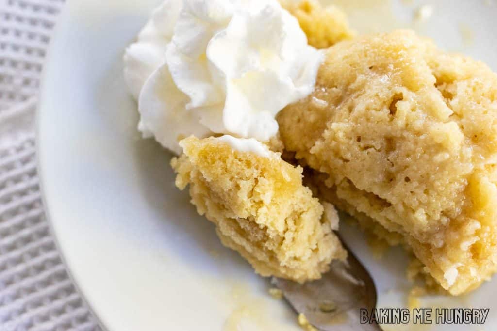 maple mug cake with a bite on a fork and a side of whipped cream from overhead